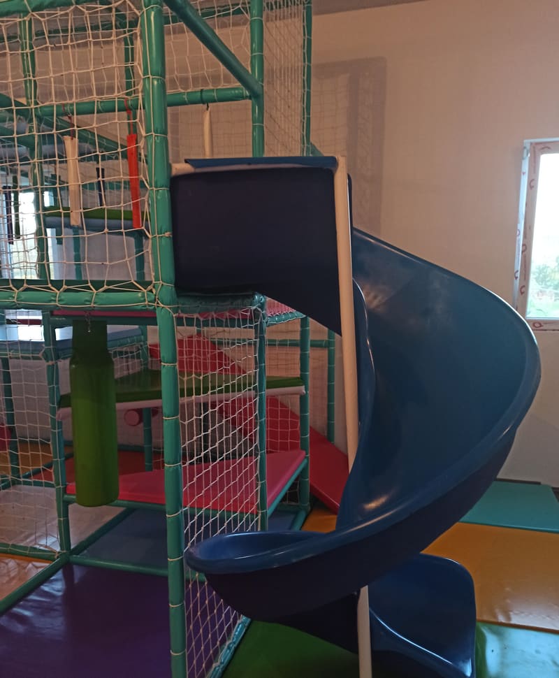 Tamnoplavi spiralni tobogan uz lavirint sa zelenim stubom