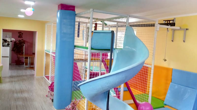 Svetloplavi spiralni tobogan iz lavirinta pored obloženog stuba i tapaciranih zidova