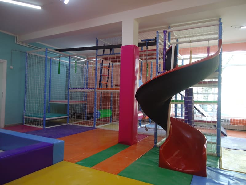 Spiralni tobogan uz obložen stub i lavirint sa mrežama, snimljen iz ugla sale